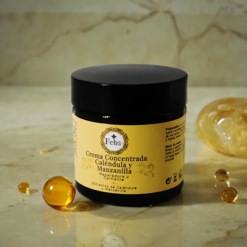 La Crema Reparadora y Calmante de Febs, cuya esencia de caléndula y manzanilla se evoca a través de unas brillantes perlas de aceite y una piedra de ámbar.